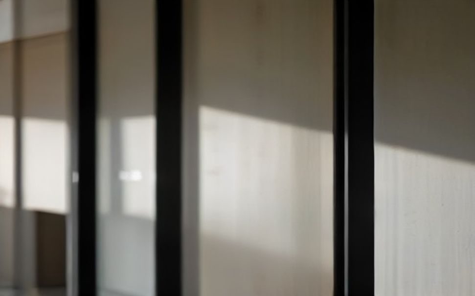 Detalhe aproximado do montante escuro de uma esquadria de alumínio contra a luz